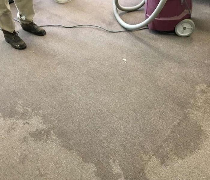 technicians boots standing on corner of water stained carpet with shop vac