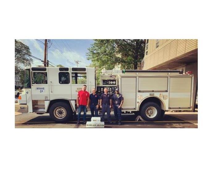 SERVPRO Sales marketing representative standing alongside new haven firefighters in front of fire truck